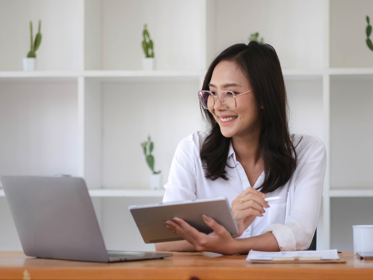Digital advertising strategist in Malaysia using a tablet and laptop to plan online marketing campaigns for local businesses.