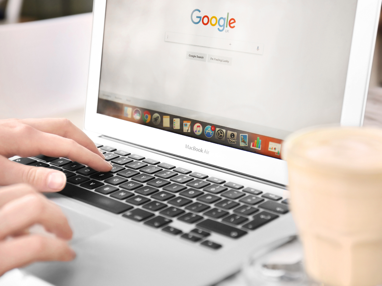Woman Using Laptop with Google on Screen in Cafe